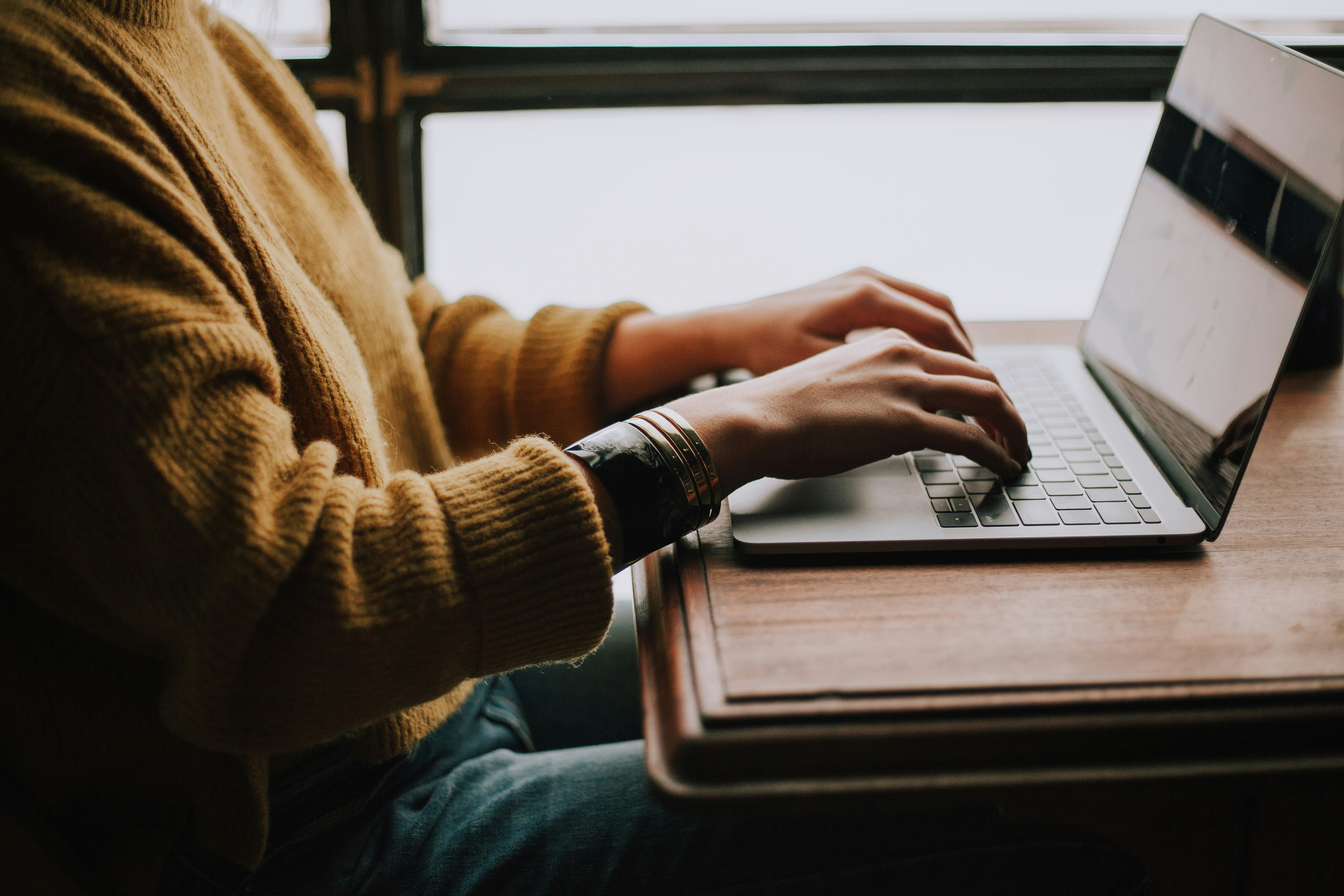 individual resting hands near open laptop