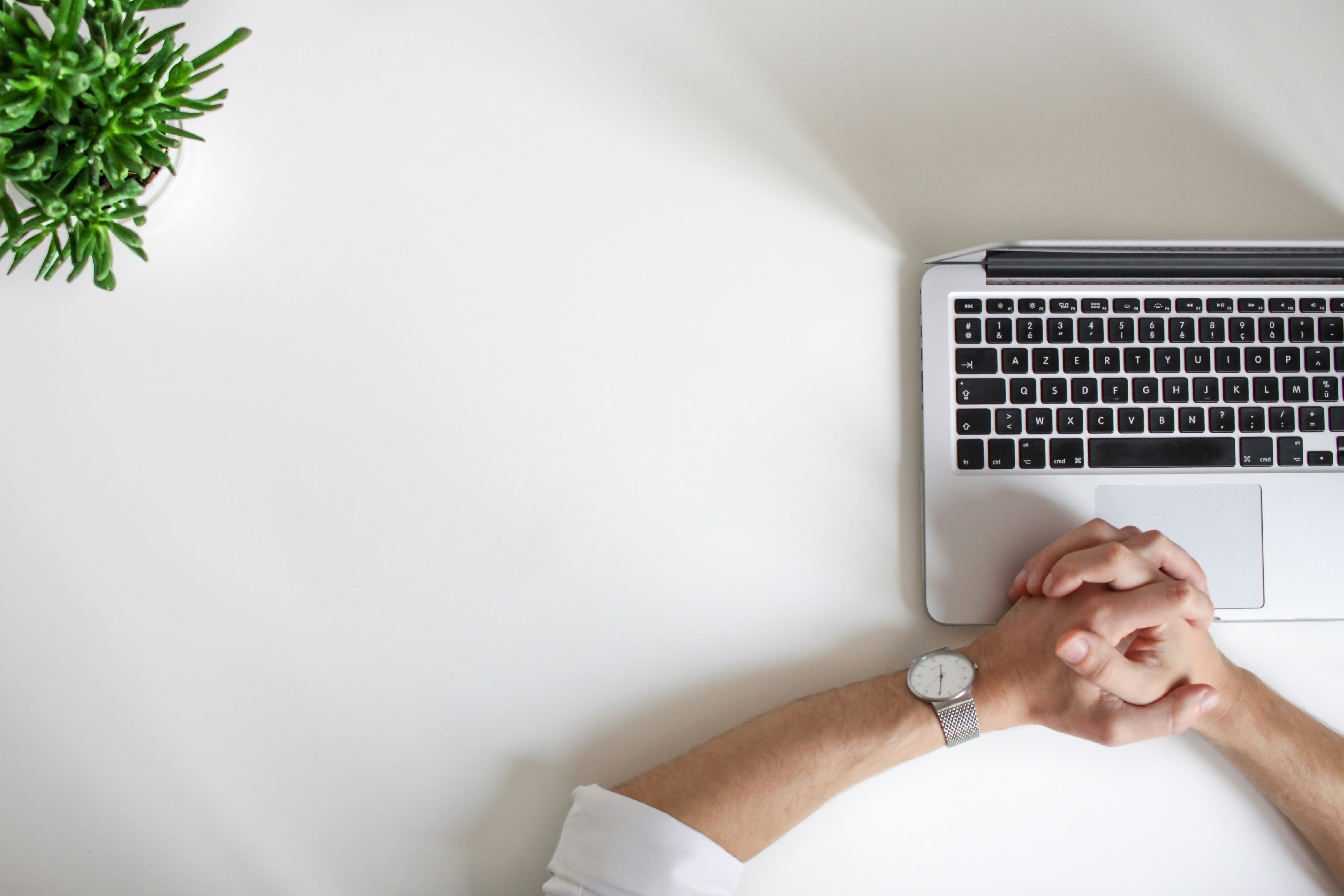 individual resting hands near open laptop
